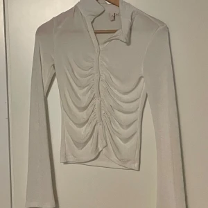Vit Långärmad topp - Säljer en superfin vit långärmad topp från nelly. Den har en cool rynkad design som ger en snygg effekt. Har aldrig använt den bara testat.💫