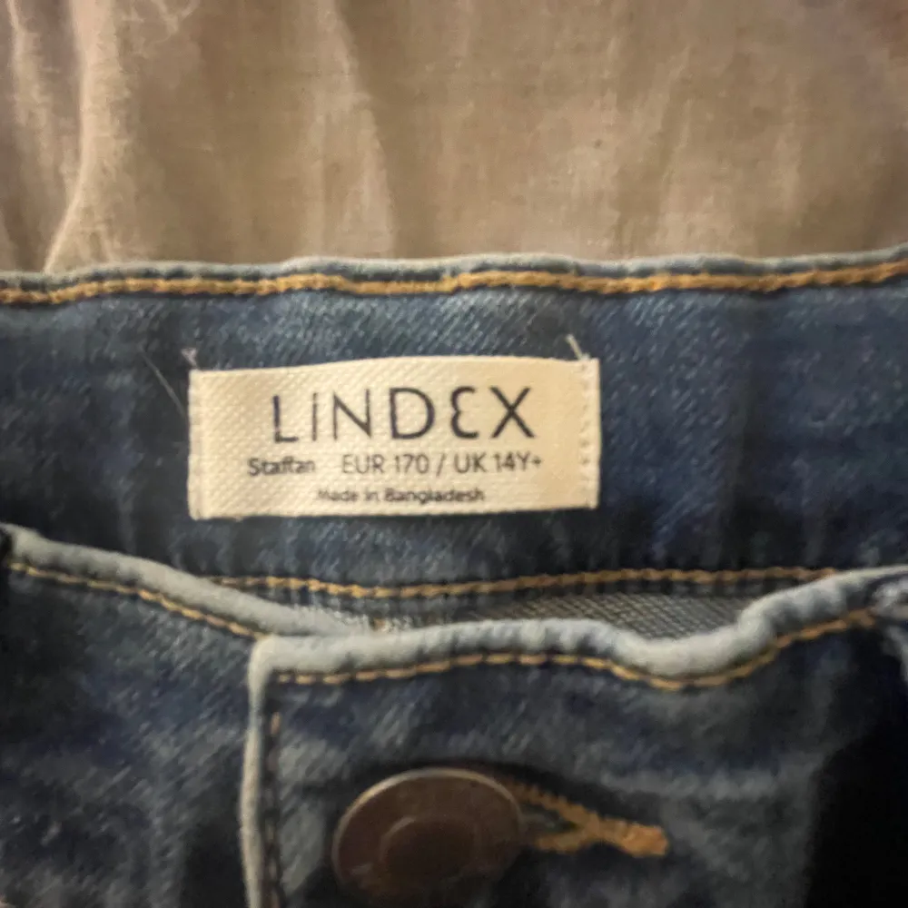 Säljer ett par snygga blå jeansshorts från Lindex i storlek 170. De är i nyskick med etiketten kvar. Shortsen har en klassisk femficksdesign och stängs med knapp och dragkedja. Perfekta för sommaren! Aldrig använda endast testade. Shorts.