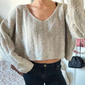 Beige stickad croppad tröja - Säljer en supermysig beige stickad tröja med v-ringning. Den är croppad och har långa ärmar, perfekt för hösten. Från zara storlek L, brukar ha xs/s för referens! 61%ull 21%akryl och 18% nylon, sticks inte alls på mig!