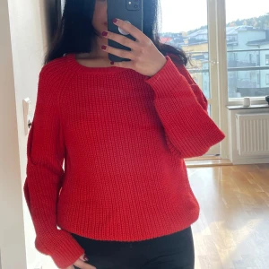 Röd/orange stickad tröja med öppna ärmar - Säljer en cool röd/orange stickad tröja med unika öppna detaljer på ärmarna. Perfekt för höst och vinter, den är både varm och trendig. Tröjan har en normal passform och är superbekväm. Köpt från NA-KD och har märket trendyol. Bra skick!