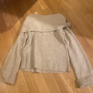 Beige offshoulder tröja från BikBok - Säljer en superfin beige offshoulder tröja från BikBok i mohairblandning. Den är perfekt för höst och vintern. Tröjan har långa ärmar och ett ribbat typ. Använd ändats ett fåtal gånger