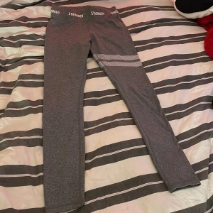 Grå träningsbyxor från Stronger - Säljer nu mina gråa träningsbyxor från Stronger. Dom är använda men har använt dom sparsamt så dom är fortfarande i fint skick. Texten i byxorna har gått bort där det står storlek men skulle säga att dom är en XS/S. Hör av dej vid intresse eller för fler bilder eller mer info. Köparen betalar frakten💕