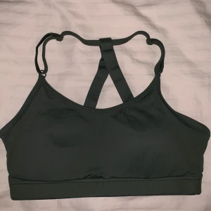 Grön sport-bh från Casall - Snygg grön sport-bh från Casall med korsade axelband och justerbara remmar. Perfekt för träning och ger bra stöd. Tillverkad i ett mjukt och stretchigt material för optimal komfort. 