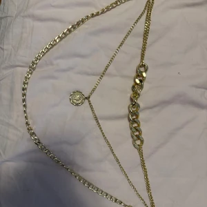 Guldhalsband med medaljong - Elegant guldhalsband med en medaljong och kedjedetaljer. Perfekt för att ge en lyxig touch till din outfit.