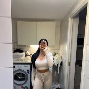 Beige myskläder set  - Säljer en stilren beige långärmad croppad topp med rund hals tillsammans med sköna formande mjukis byxa. Perfekt för en avslappnad look.