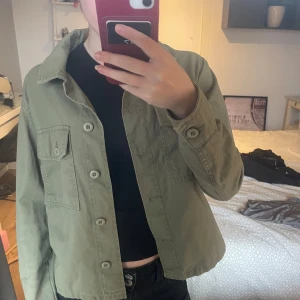 Grön overshirt med knappar - Snygg grön overshirt med knappar framtill och en bröstficka. Perfekt för lager-på-lager-stil. Passar bra till både jeans och kjol.