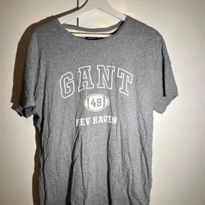 Grå t-shirt från GANT - Snygg grå t-shirt från GANT med tryck framtill. Perfekt för en avslappnad stil. Tillverkad i mjukt material för extra komfort.