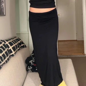 Svart långkjol - Snygg svart långkjol med en tight passform. Perfekt för en stilren look. Kjolen är enkel och elegant, vilket gör den lätt att matcha med olika toppar och accessoarer.