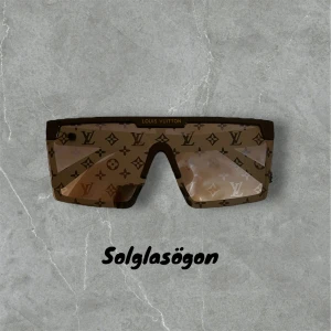 Solglasögon  - Snygga solglasögon med mönster och logotyp på glasen. De har en modern, rektangulär form och svarta skalmar med guldfärgad logotyp på sidan. Perfekta för en stilren look.