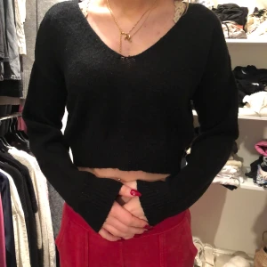 Svart croppad tröja från NA-KD - Säljer en svart croppad tröja från NA-KD med v-ringning. Tröjan har långa ärmar och är perfekt för en trendig look. Passar bra till både kjol och byxor.