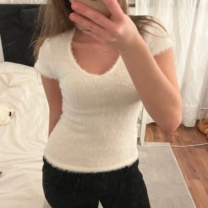 Vit fluffig topp - Säljer en supermjuk och fluffig vit topp med korta ärmar och v-ringning, sjukt snygg till utgång eller bara till vardags. Den är i strl M men sitter ganska tight o är liten i strlk, så sitter även otroligt snyggt på S-XS. Nyskick med prislappen kvar! Hör av er om funderingar💗💗💗