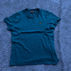  Lyle&Scott T-shirt - Snygg blå t-shirt från Lyle & Scott med deras ikoniska logga på bröstet. Passar 12-13 år som är runt 160-165 cm. Vid fråga eller fundering hör av dig!