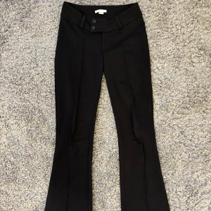 Lågmidjade kostymbyxor - Snygga svarta kostymbyxor med låg midja och bootcut. Byxorna har två knappar framtill och dragkedja. Är i storlek 164 men passar som xs. Endast testade🩷