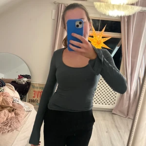 Mörkgrön långärmad topp - Säljer en stilren mörkgrön långärmad topp med en djup rund halsringning från Gina tricot. Perfekt för lager-på-lager eller som den är. Passar till både jeans och kjol.