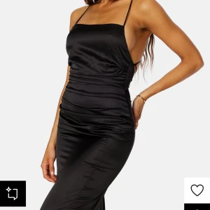 Svart långklänning/balkläning  - Från bubbleroom. Elegant svart långklänning med smala axelband och korsad rygg. Klänningen har en figurnära passform och är tillverkad i ett glansigt material som ger en lyxig känsla. Perfekt för speciella tillfällen/balen! Använd 1 gång.