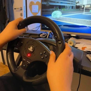 Ratt och pedaler för PlayStation - Säljer en ratt och pedalset för PlayStation. Ratten har flera knappar inklusive R2, L2, och en PS-knapp i mitten. Pedalerna är svarta och har en stabil bas. Perfekt för racing-spel och ger en realistisk körupplevelse. Ansluts via USB.