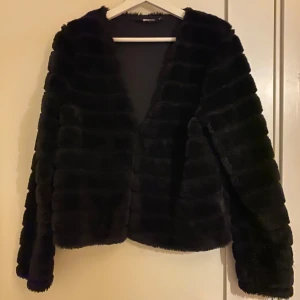 Svart pälsjacka från Gina Tricot - Snygg svart pälsjacka från Gina Tricot i storlek M. Jackan har en elegant design med långärmade ärmar och är perfekt för att hålla dig varm och stilren under kyliga dagar.