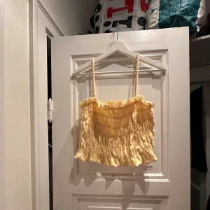 Frotté topp - Söt gul topp i frotté med volangdetaljer. Perfekt för sommardagar. Toppen har en elastisk passform som gör den bekväm och lätt att bära. Den är i mycket bra skick och redo för nya äventyr!