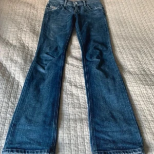 Blå jeans från Diesel - Säljer ett par snygga blå jeans från Diesel i bra skick. De har en klassisk femficksdesign och en bootcut-stil som ger en retro vibe. Perfekta för både vardag och fest! 🕺400 kr vid snabb affär!!!