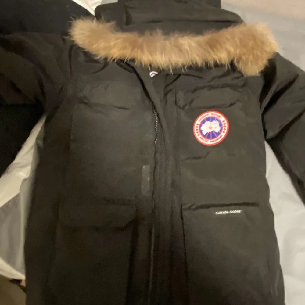 Säljer en svart Canada Goose dunjacka i mycket bra skick. Jackan har en pälsfodrad huva och är perfekt för kalla vinterdagar. Den har en dragkedja framtill och är långärmad. Märkets logga syns tydligt på bröstet. Perfekt för dig som vill hålla värmen med stil!. Jackor.