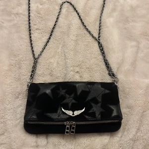 Svart axelväska med stjärnor och kedja - Jätte snygg Zadig & Voltaire väska. Knappt använd ca 5 gånger, jätte bra skick. Skriv om ni vill ha med info eller fler bilder. Pris kan diskuteras.