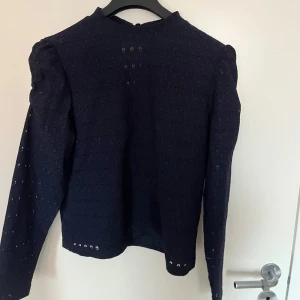 Marinblå spetsblus - Säljer en elegant marinblå spetsblus med långa ärmar. Perfekt för höst och vinter, den har en fin struktur och är i mycket bra skick. Passar både till vardags och festliga tillfällen. 