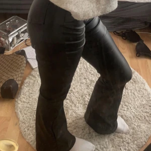 Svarta skinnbyxor - Säljer ett par snygga svarta skinnbyxor i bootcut. dem sitter väldigt fint på och är knappt använda. jag skulle säga att dem är mid-rise men att man kan vika ner dem till low-rise om man vill det. passar 32/34