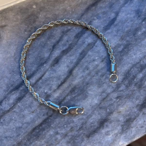 Silverfärgat armband i tvinnad design - Snyggt och stilrent armband i silverfärgad metall med en tvinnad design. Perfekt för både vardag och fest. Armbandet har en praktisk karbinhake som gör det enkelt att ta på och av. Passar de flesta handleder och ger en elegant touch till din outfit.