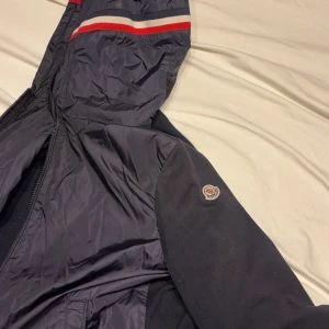 Mörkblå jacka från Moncler - Säljer en snygg mörkblå jacka från Moncler. Skick 8/10 lite solblekt men inget man tänker på, då det inte syns så mycket. Det är M men passar mer för dig som bär Strl S. Köpte den på Plick i somras, fick inte med kvitto eller något med jackan men den är legit checkad och scanar man qr coden så kommer man in där man ska komma in! Pris ej huggit i sten och fundera verkligen inte på att höra av er! (Köparen står för frakt)