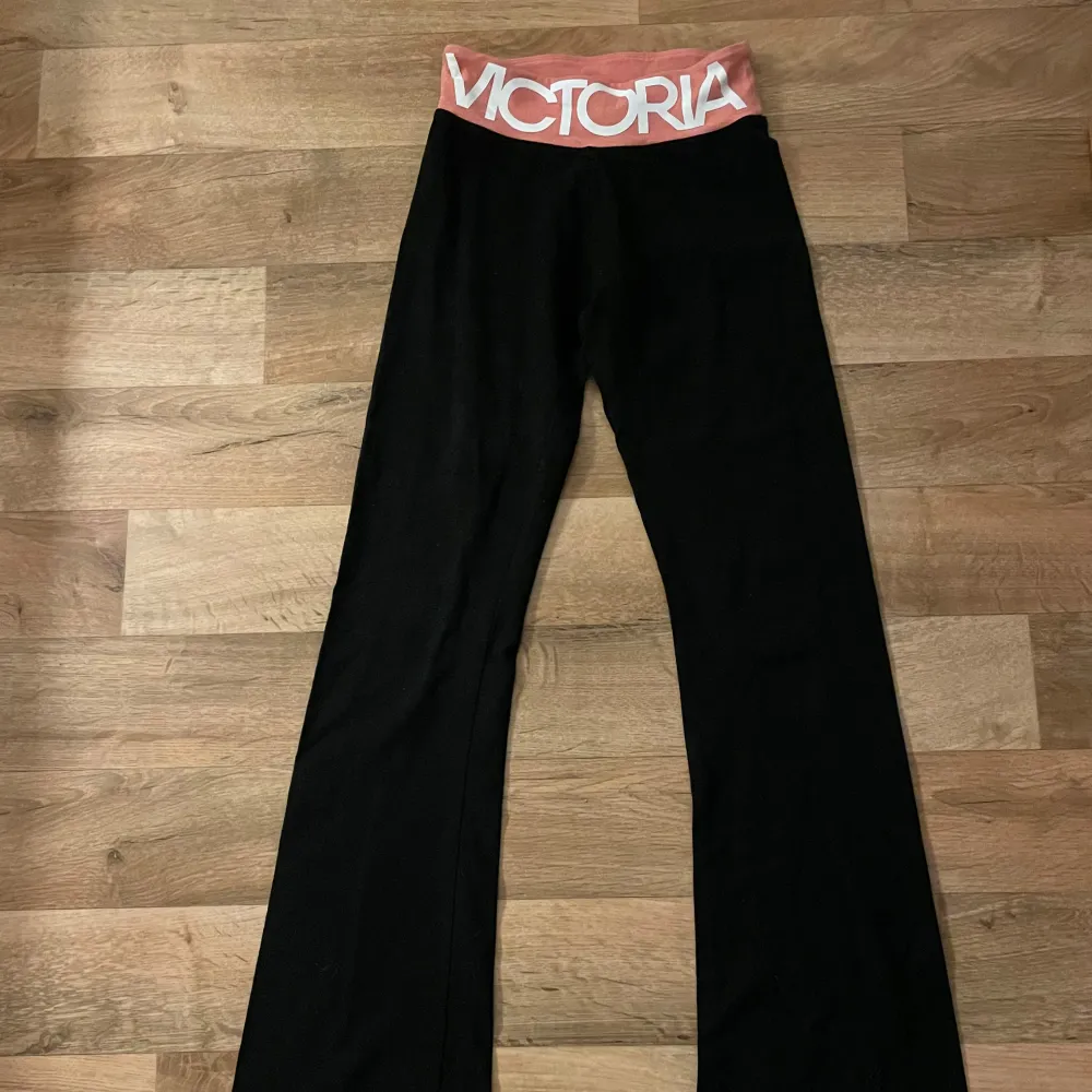 Läs info 🎀Säljer ett par svarta träningsbyxor från Victoria Sport. De har en låg midja  med en bred rosa resår där det står 'VICTORIA' i vitt. Trycket är på framsidan , dom är inte stretchiga . Jeans & Byxor.