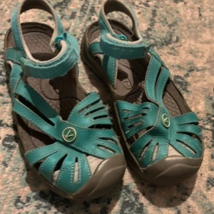 Turkosa sandaler från Keen - Säljer ett par turkosa sandaler från Keen i mycket bra skick. De har en bekväm passform med justerbara remmar och en robust sula för bra grepp. Perfekta för sommarens äventyr eller en dag på stranden. Sandalerna är både snygga och praktiska! Har även en täckt tå som gör att eg skyddar foten mer.