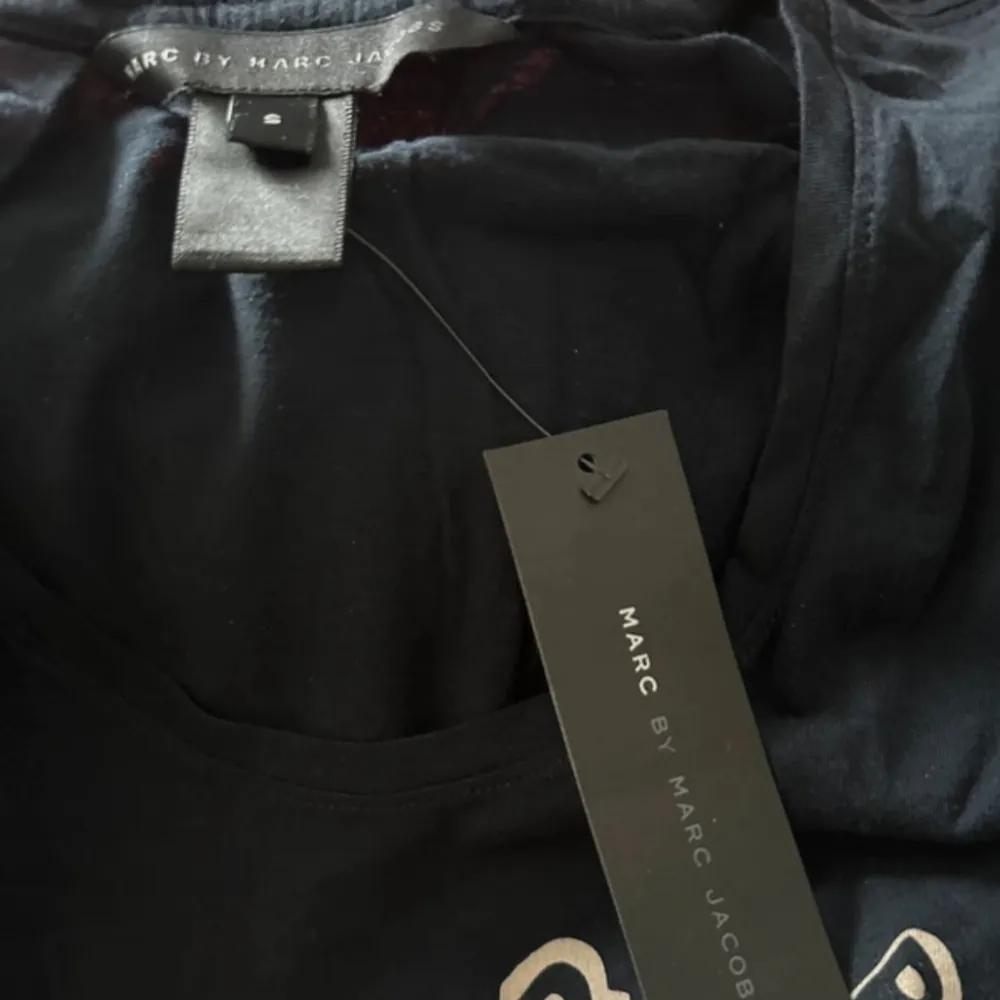 Säljer en snygg svart t-shirt från Marc by Marc Jacobs med texten 'I ❤️ Marc by Marc Jacobs' i en cirkel på framsidan. T-shirten är oanvänd och perfekt för vardagsbruk. T-shirts.