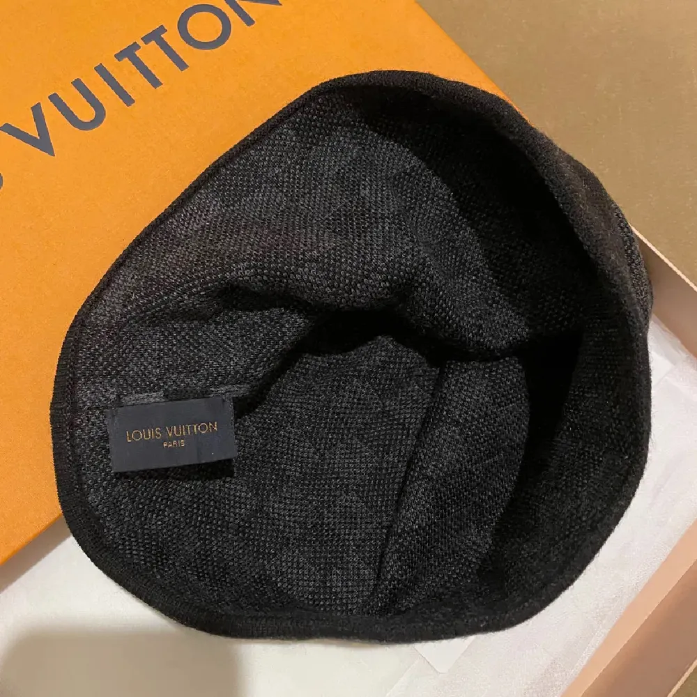 Säljer en snygg svart mössa från Louis Vuitton med klassiskt rutmönster. Mössan är i mycket bra skick och kommer i originalförpackning. Perfekt för höst och vinter, och den har en diskret LV-logga framtill. Passar både till vardags och lite finare tillfällen.. Accessoarer.