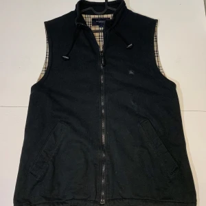 Burrberry väst - En riktigt fet väst från märket Burrberry. Färgen är svart, storleken L men jag skulle säga att den passar mer som en M. Den är är använd men har inga defekter, skick 7,5/10.