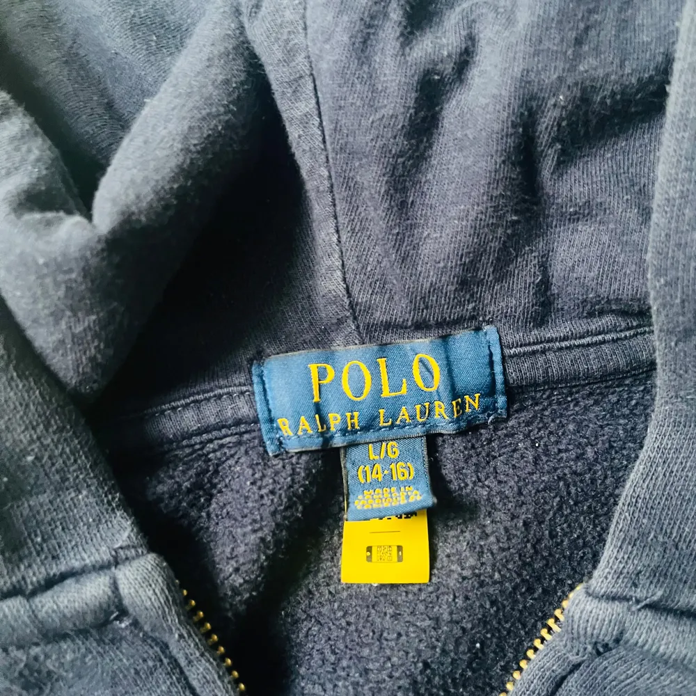 Säljer en snygg mörkblå hoodie från Ralph Lauren med dragkedja och det klassiska röda logotypbroderiet på bröstet. Perfekt för höst och vinter, med en mysig och varm känsla. Passar både till vardags och chilliga dagar. . Tröjor & Koftor.