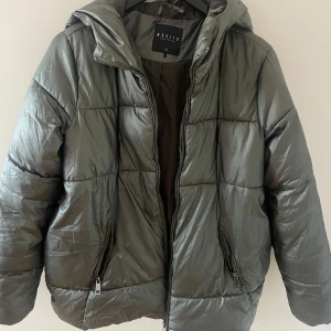Grön jacka - En grön och glansig pufferjacka perfekt till vintern i mycket bra skick😊den är ursprungligen från mohito collection, ganska stor i storleken S/M