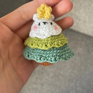 Handgjord nyckelring med virkad figur - Supergullig handgjord nyckelring med en virkad figur som ser ut som en liten gran med stjärna på toppen. Den har lager i vitt, grönt och blått garn, och en söt liten ansikte med rosa kinder. Perfekt som en unik accessoar till väskan eller nycklarna!