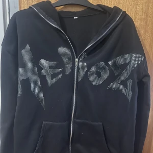Y2k hoodie - Säljer en svart hoodie med dragkedja och glittrig text på framsidan. Perfekt för en cool och avslappnad stil. Den har en bekväm passform och är idealisk för både vardag och fest. Hör av dig om du är intresserad! ✨