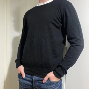 Svart merinoull tröja - Säljer en stilren svart tröja i merinoull. Perfekt för både vardag och fest. Tröjan har en normal passform och långa ärmar, vilket gör den idealisk för höst och vår. Enkel och snygg design som passar till det mesta. 