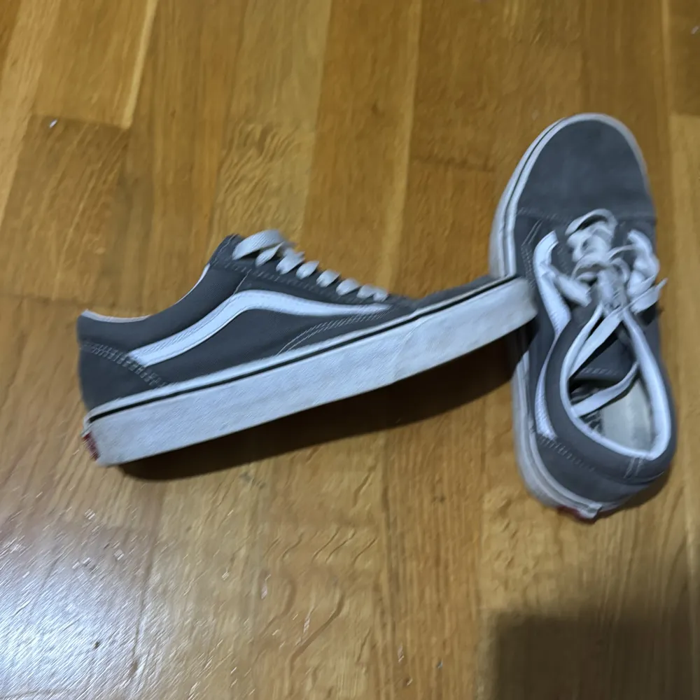 Säljer ett par gråa Vans sneakers i storlek 40. De har en klassisk design med vit sula och snörning. Skorna är i välanvänt skick men fortfarande bekväma och perfekta för vardagsbruk. Passar bra till både jeans och shorts! Använt skick . Skor.