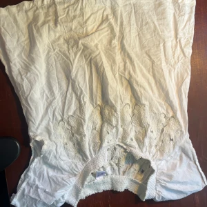 Vit ärmlös topp med broderi - Säljer en vit ärmlös topp med vackert broderi på framsidan. Toppen har en luftig och bekväm passform, perfekt för varma sommardagar. Den är i bra skick och redo för nya äventyr!