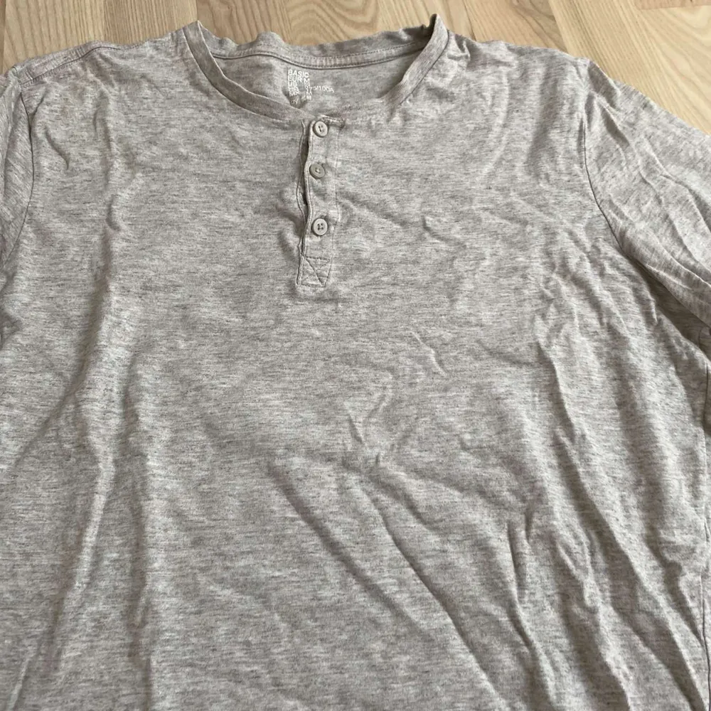 Säljer en grå t-shirt från H&M i storlek M. Den är kortärmad och har tre knappar vid halsen för en avslappnad look. Perfekt för vardagsbruk och gjord i mjukt bomullsmaterial.. T-shirts.