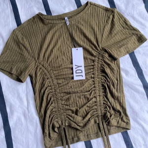 Olivgrön JDY topp - En super fin olivgrön T-shirt🍂 Jag säljer den just för att den aldrig kommit till användning ursprungspriset är 229kr men säljer den för 50kr