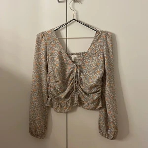Blommig blus med volangdetaljer - Säljer en superfin blommig blus från HM i storlek S. Den har långa ärmar och en söt volangdetalj framtill. 