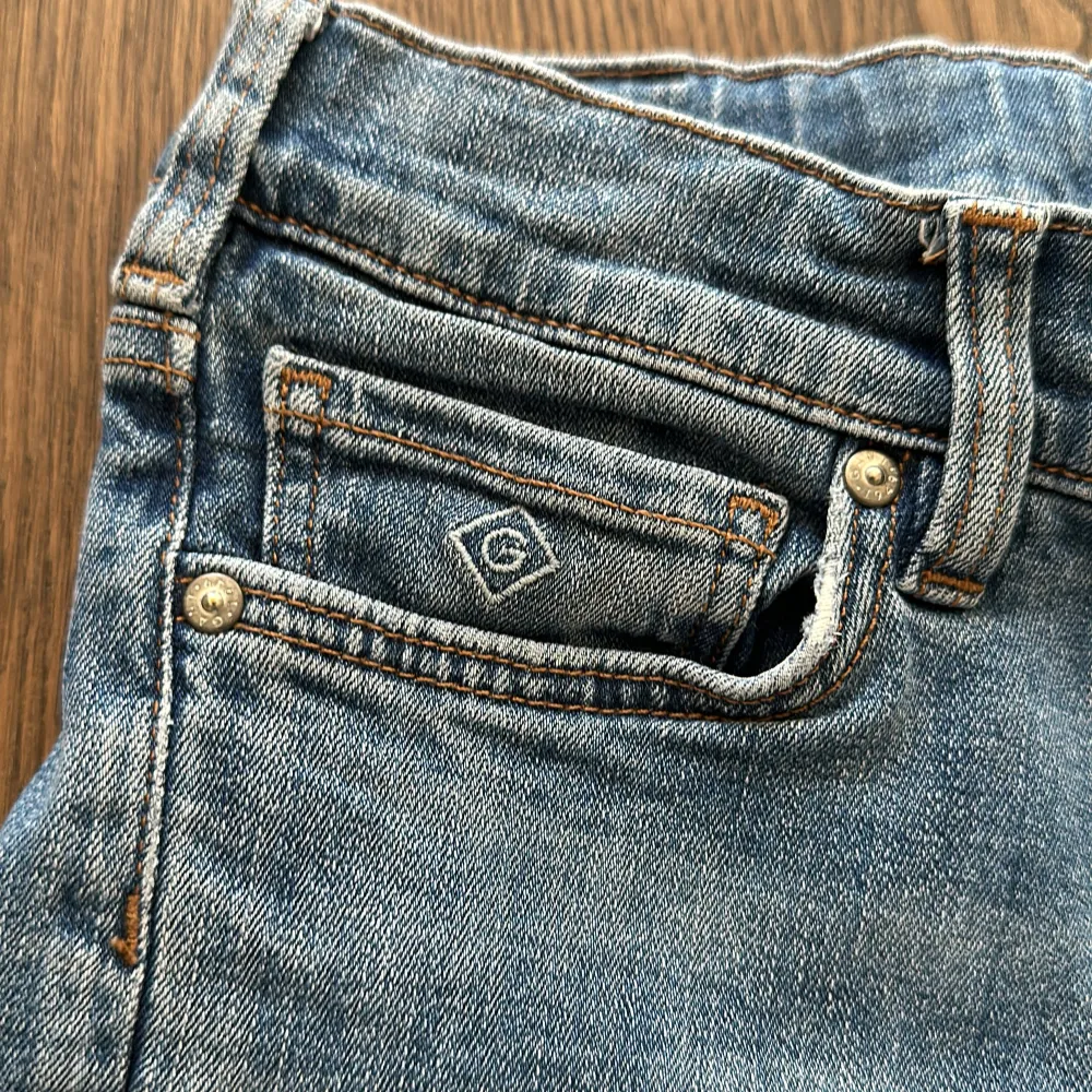 Säljer ett par snygga jeansshorts i blå denim. De har en klassisk femficksdesign med en liten logga på den lilla fickan fram. Shortsen har en knappgylf och är i en bekväm längd som slutar strax ovanför knäna. Perfekta för sommardagar!. Shorts.