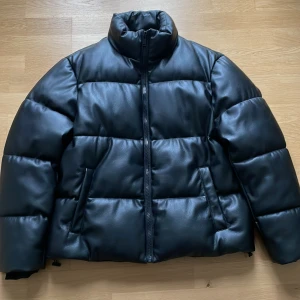 Svart pufferjacka från Zara unisex Ny - Säljer en NY snygg svart pufferjacka från Zara i storlek L. Unisex modell Jackan är i skinn look  och har en dragkedja framtill Perfekt för kalla dagar. 