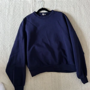 Mörkblå sweatshirt från Nelly - Säljer en snygg och bekväm mörkblå sweatshirt från Nelly. Perfekt för en avslappnad stil med långa ärmar och mjukt material. Passar perfekt till både jeans och mysbyxor. Ett måste i garderoben för alla som älskar en casual look!
