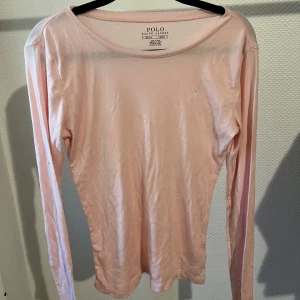 Polo Ralph Lauren tröja - Säljer en superfin ljusrosa långärmad tröja från Polo Ralph Lauren. Den är i ett mjukt bomullsmaterial och har en liten broderad logga på bröstet. Perfekt för både vår och höst! 💖