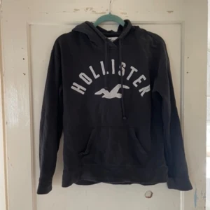 Svart hoodie från Hollister - Säljer en svart hoodie från Hollister i storlek M. Den är supermjuk och perfekt för kyliga dagar. Hoodien har en stor ficka fram och justerbar huva med snören. Den är i bra skick och redo för nya äventyr!