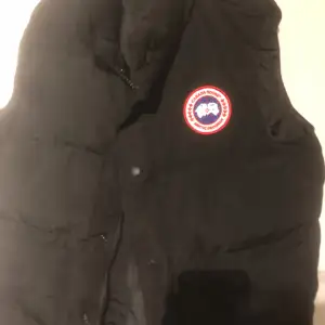 Säljer en svart dunväst från Canada Goose i mycket bra skick. St S. Qr funkar som den ska